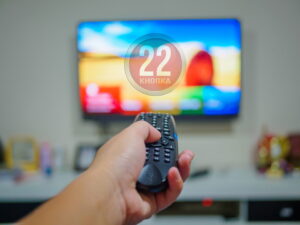 22-knopka1-300x225 Close,Up,Hand,Holding,Tv,Remote,Control,With,A,Television